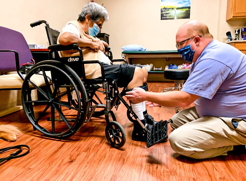 Male orthotist fitting leg brace on woman in wheelchair