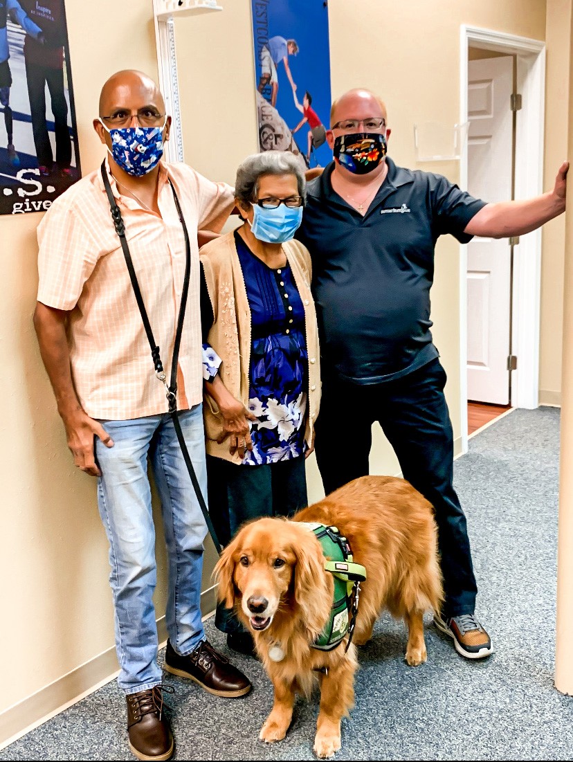 man, woman, standing with orthotist and service dog